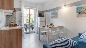 A modern kitchen with a wooden countertop, a dining area with white chairs, and a balcony with a view.