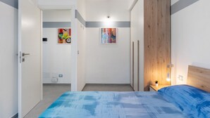 A bedroom with a bed, a nightstand, a wooden headboard, and two wall-mounted light fixtures.