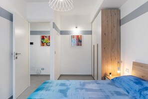 A bedroom with a bed, a nightstand, a wooden headboard, and two wall-mounted light fixtures.