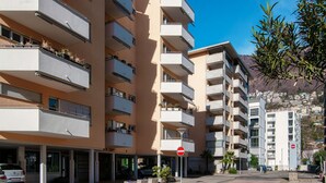 A multi-story residential building with balconies, a parking area, and a clear blue sky. - Studio apartment a few steps from Piazza Grande and the lakefront (CITY 1) (Locarno)