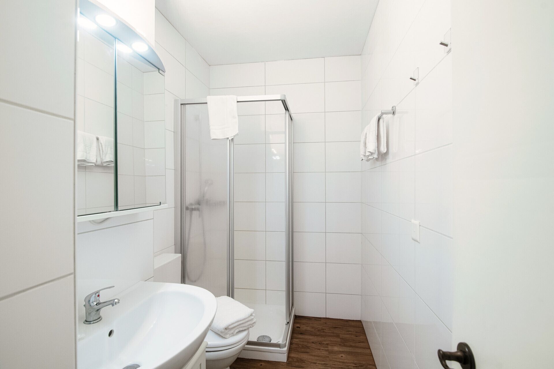Un bany compacte amb dutxa d'envidriament, un lavabo blanc i un vàter.