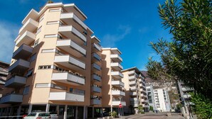 A multi-story residential building with balconies, a parking area, and a clear blue sky. - Studio apartment a few steps from Piazza Grande and the lakefront (CITY 1) (Locarno)
