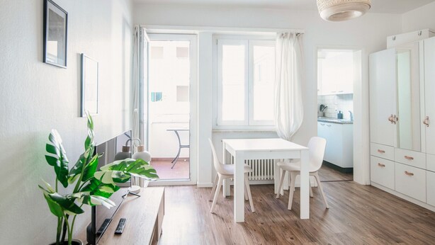 A bright, modern room with a white table and chairs, a radiator, and a view through a large window. - Studio apartment a few steps from Piazza Grande and the lakefront (CITY 1) (Locarno)