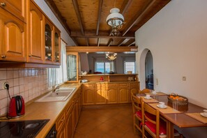 A kitchen with wooden cabinets, a sink, a stove, and a dining area with chairs and a table.