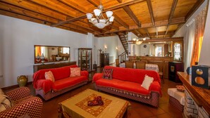 Un amplio salón con dos sofás rojos, techo de madera y una cocina al fondo.