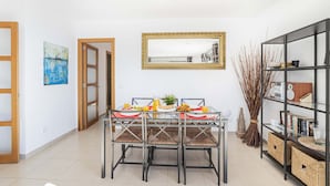 A dining area with a glass table, metal chairs, and a buffet cabinet. - Apartamento Bellavista Puerto 2A (Cala Ratjada)