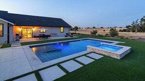 A modern house with a swimming pool, a patio with outdoor furniture, and a well-maintained lawn. - Brand-new Farmhouse Style Ranch w/Fire Pit in the heart of Paso Robles! (Paso Robles)