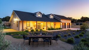 A two-story house with a covered patio, outdoor seating, and a landscaped garden. - Brand-new Farmhouse Style Ranch w/Fire Pit in the heart of Paso Robles! (Paso Robles)