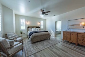 A spacious bedroom with a large bed, a ceiling fan, a wooden dresser, and a view of the outdoors through a window. - Brand-new Farmhouse Style Ranch w/Fire Pit in the heart of Paso Robles! (Paso Robles)