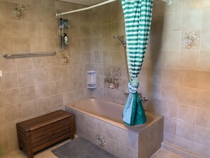 Een bad/douchecombinatie, een haardroger, handdoeken, toiletpapier