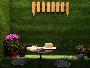 A garden setting with a wooden fence, a round table with a hat and book, and potted plants. - Athens City View Urban Suites (Athens)