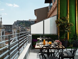 A rooftop terrace with a table set for dining, overlooking a cityscape with historical buildings and a hill in the background. - Athens City View Urban Suites (Athens)