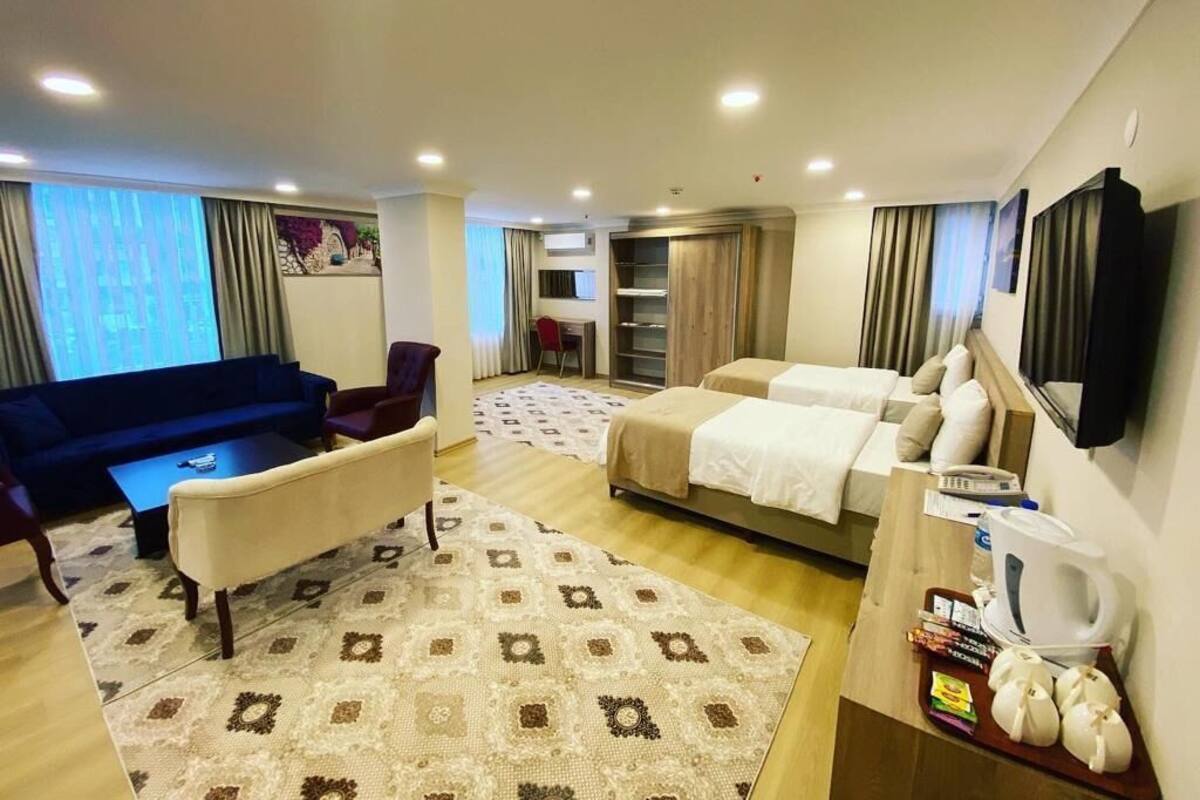 A hotel room with a sofa, a bed, a coffee table, a TV, and a coffee maker.