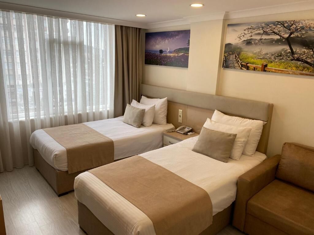 Habitació d'hotel amb dos llits, una tauleta de nit i un quadre penjat a la paret.