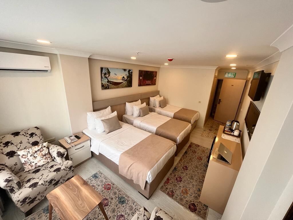 Una habitación de hotel con cama, sofá, escritorio y televisor.