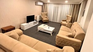 A modern living room with a large beige sofa, two armchairs, a coffee table, and a flat-screen TV. - Şimal Hotel (Rize)