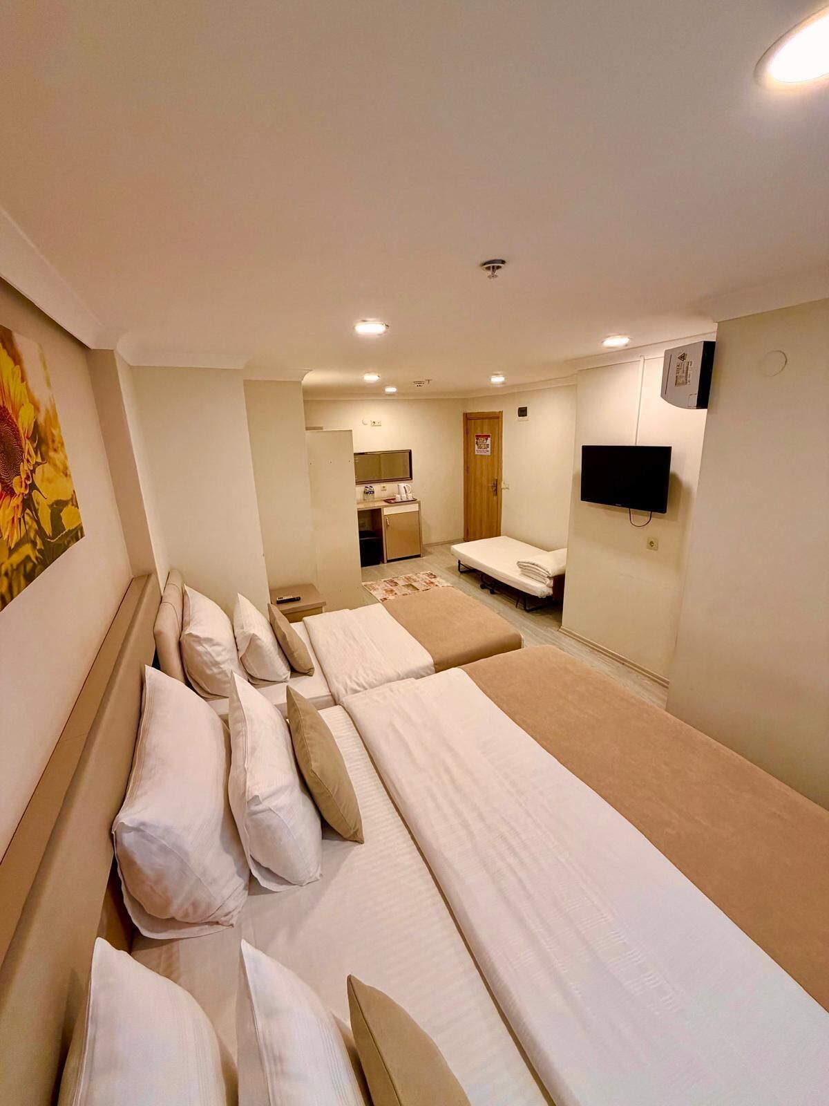 Habitación de hotel con dos camas, televisión, escritorio con silla y baño.