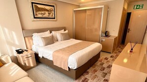 A hotel room with a bed, bedside table, chair, and a small table with fruit. - Şimal Hotel (Rize)