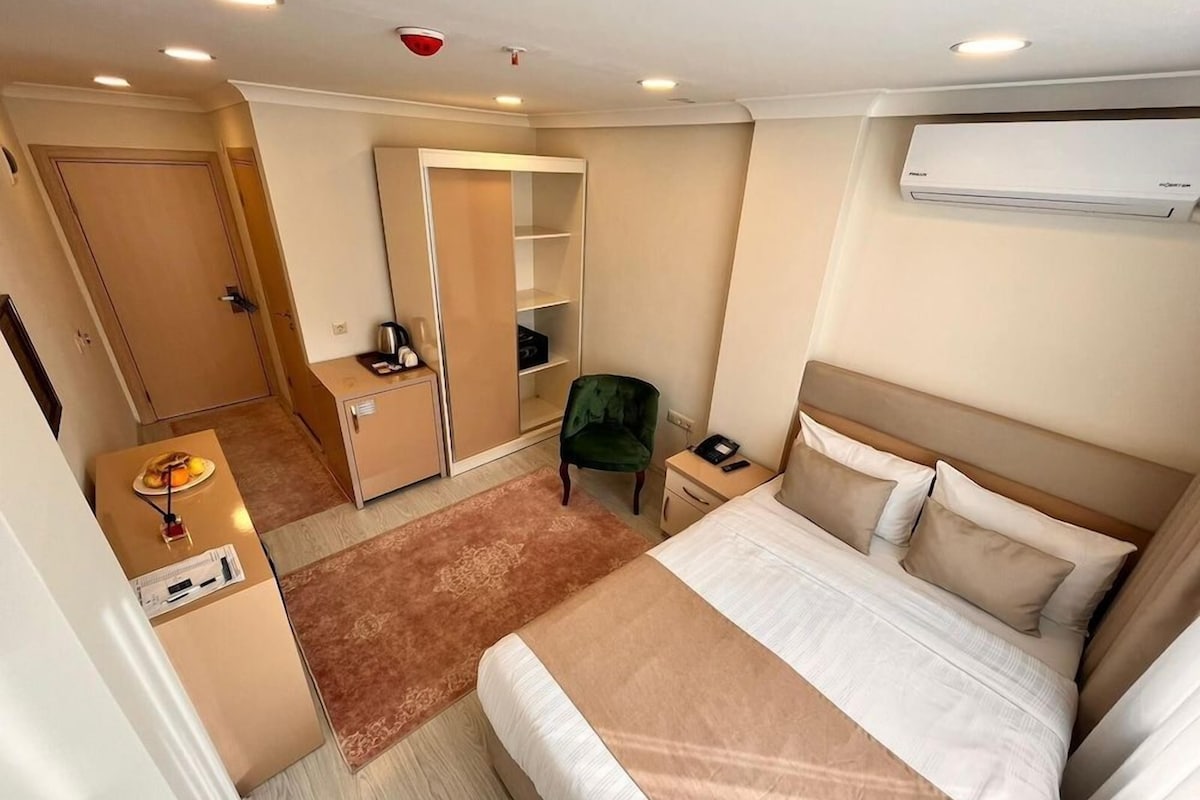 Ett hotellrum med en säng, ett sängbord, en nattduksbord, en garderob och ett skrivbord med en stol.