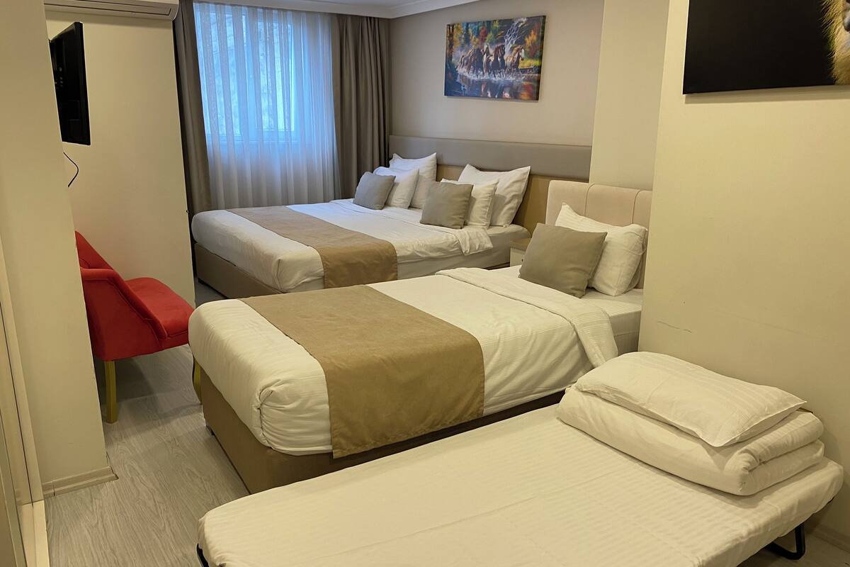 A hotel room with two beds, a red chair, and a painting on the wall.