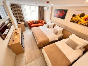 Una habitación de hotel con dos camas, un sofá, un televisor y obras de arte en las paredes.