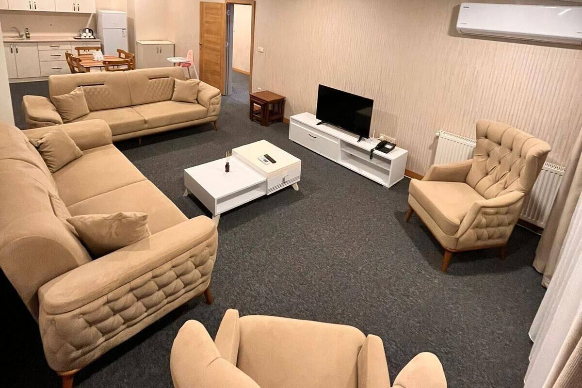 A living room with a sofa, armchair, coffee table, TV, and a small side table.