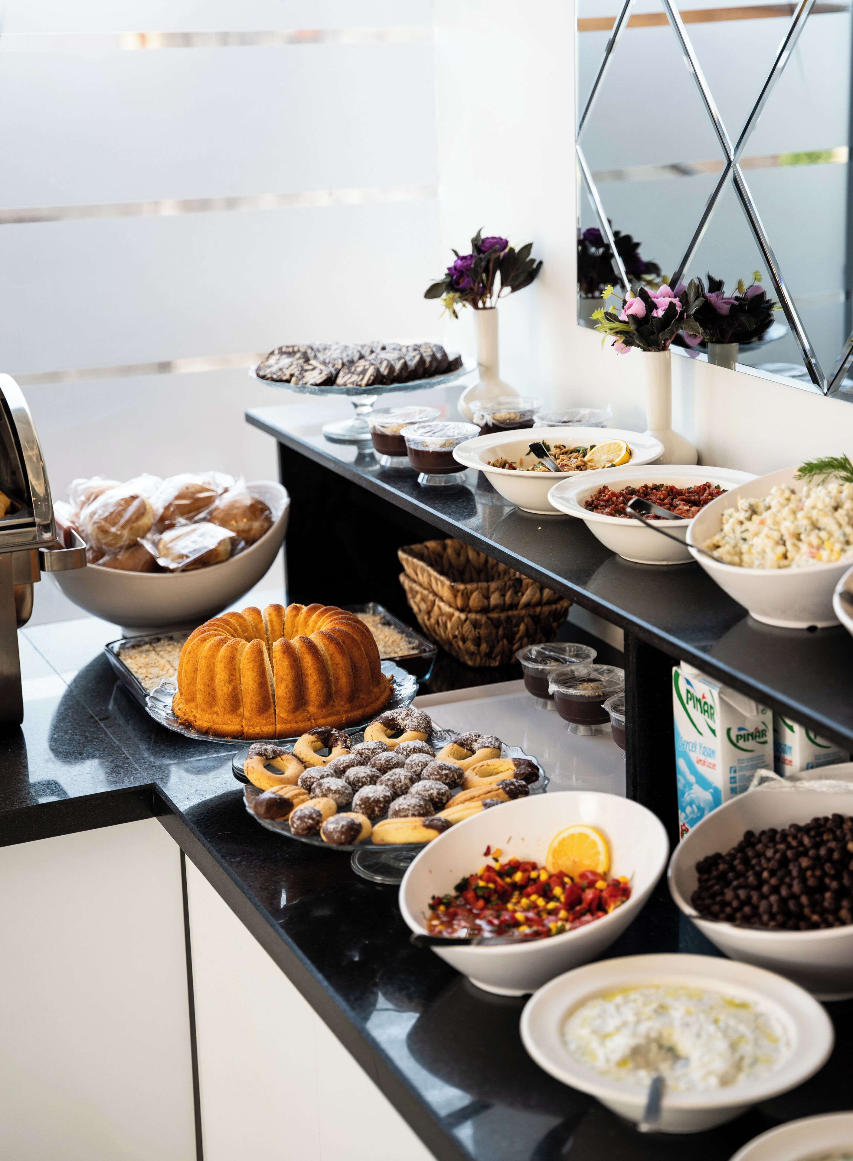A buffet table with various food items including a bundt cake, pastries, and bowls of salad and other dishes.
