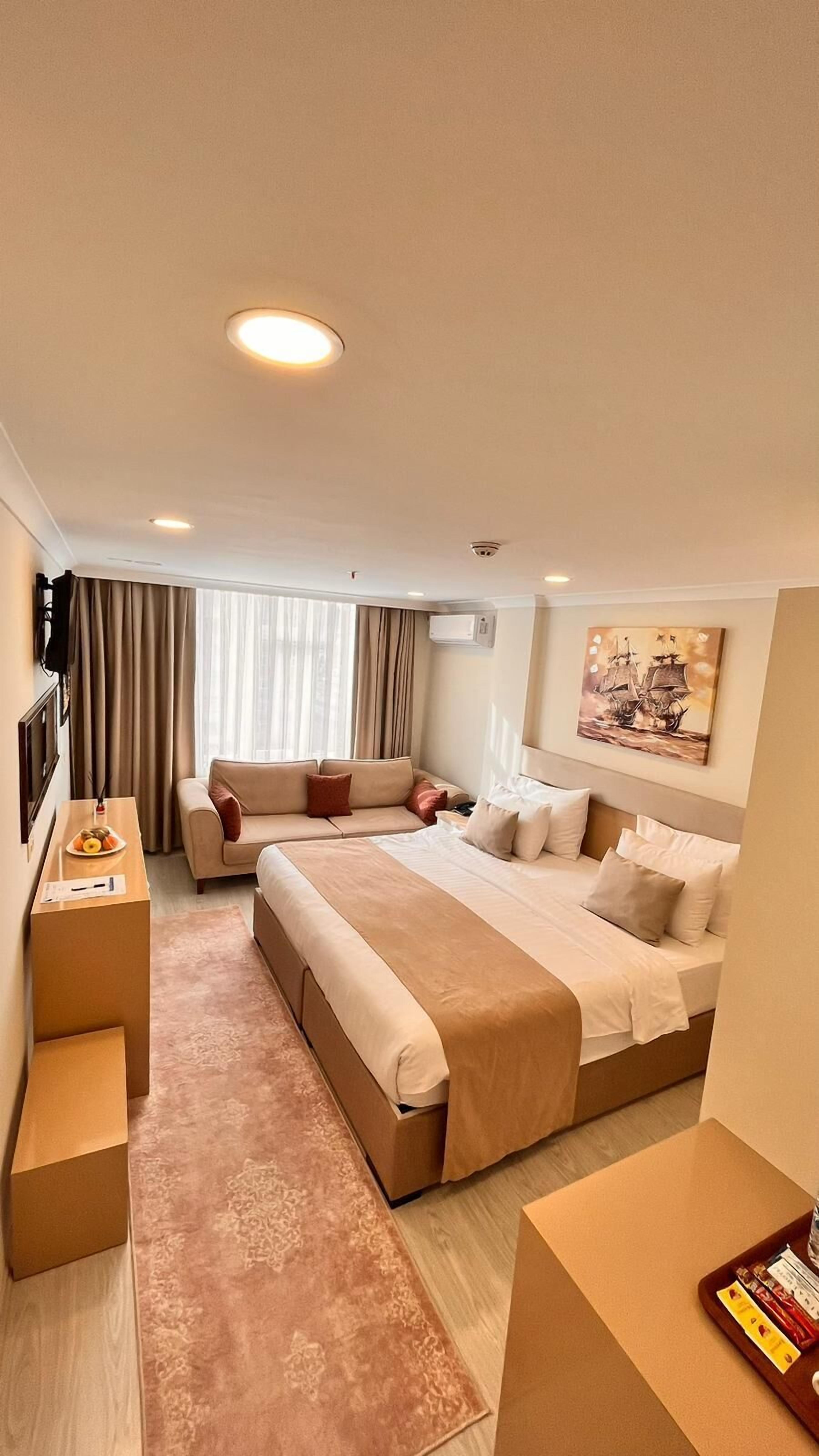 Una camera d'albergo con un letto grande, un divano, una scrivania e un quadro appeso al muro.