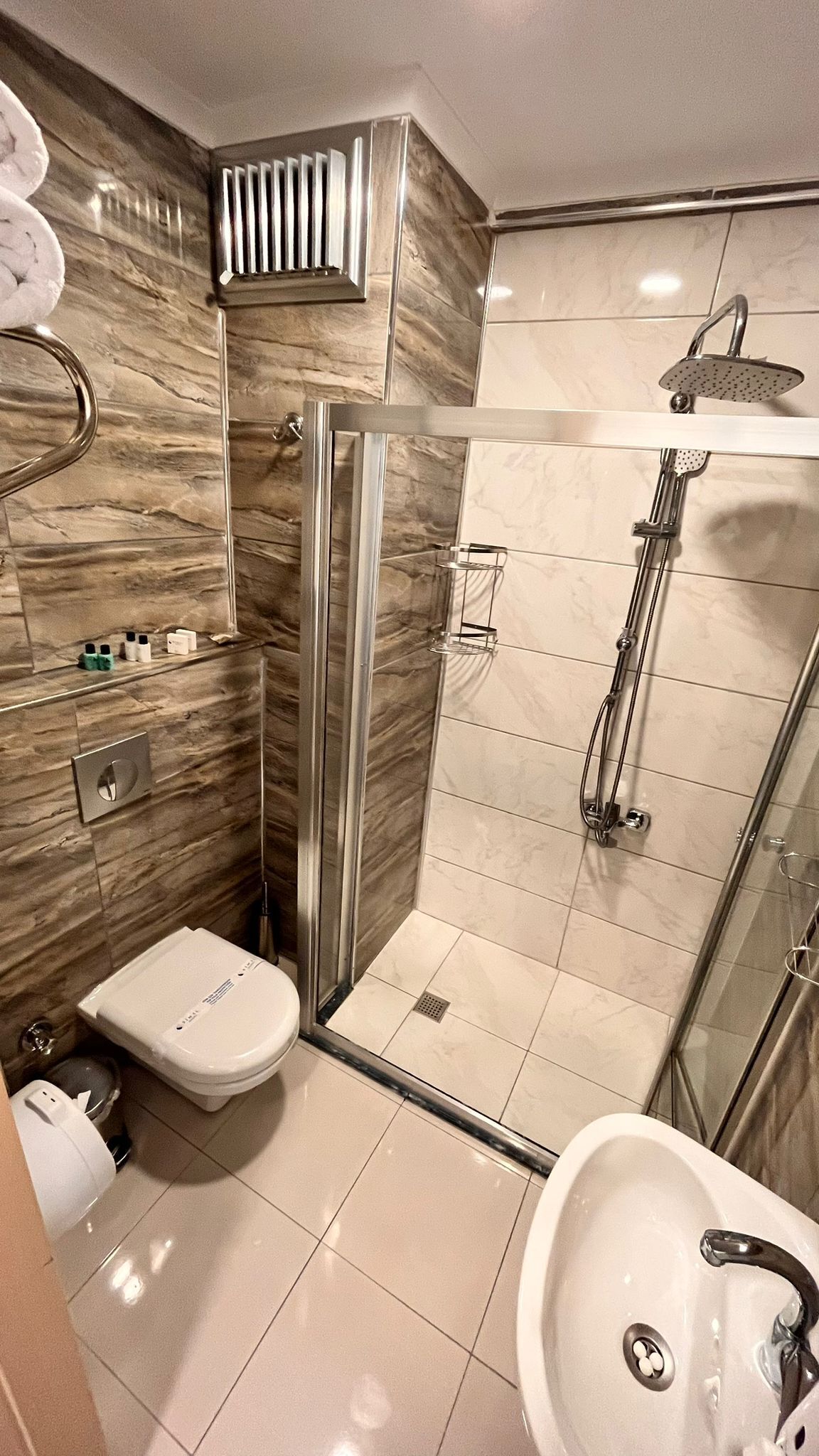 Un baño moderno con ducha envuelta en vidrio, inodoro y lavamanos.