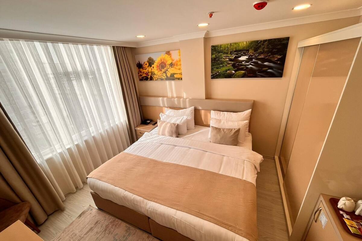 A hotel room with a large bed, a nightstand, a lamp, and a painting on the wall.