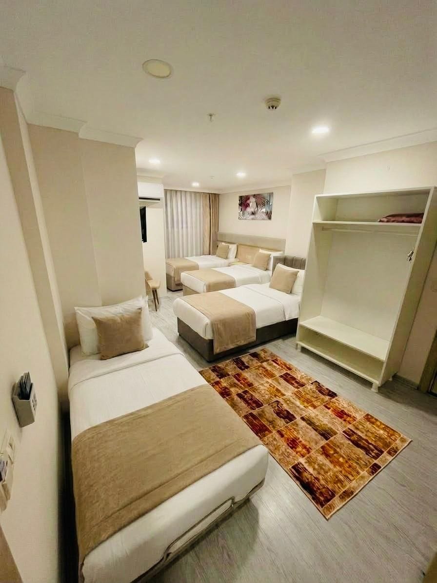 A hotel room with two beds, a wardrobe, and a patterned rug.