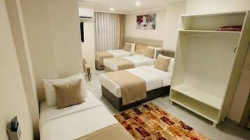 A hotel room with two beds, a wardrobe, and a patterned rug.