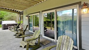 A covered patio with wooden rocking chairs, a grill, and a view of the outdoors. - Canadian Day by Taylor Made Deep Creek (McHenry)