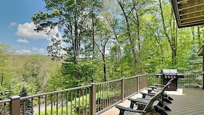 A deck with picnic tables and a grill, overlooking a forested area. - Canadian Day by Taylor Made Deep Creek (McHenry)