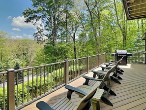 Eine Terrasse mit Picknicktischen und Grill, mit Blick auf ein bewaldetes Gebiet.