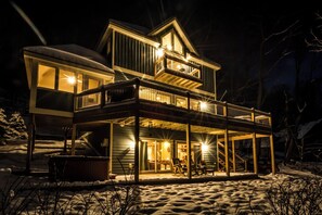 A two-story house with a covered porch and a balcony, surrounded by snow. - Canadian Day by Taylor Made Deep Creek (McHenry)