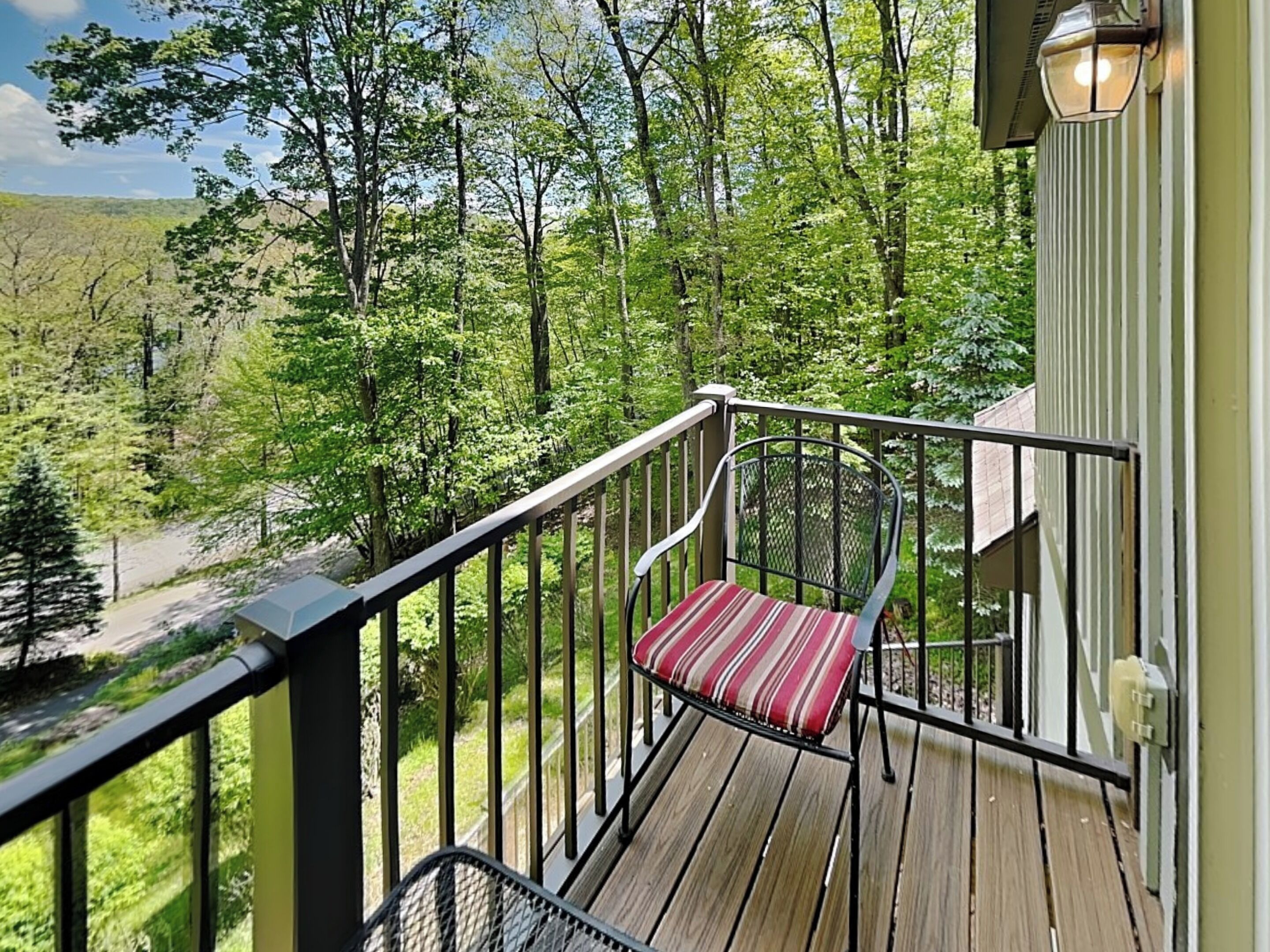A deck with a chair and a railing overlooking a forested area.