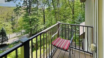 A deck with a chair and a railing overlooking a forested area.