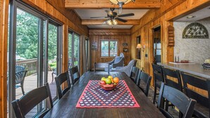 A wooden interior with a dining table, chairs, and a fruit bowl. - Canoe Cottage by Taylor Made Deep Creek (Oakland)