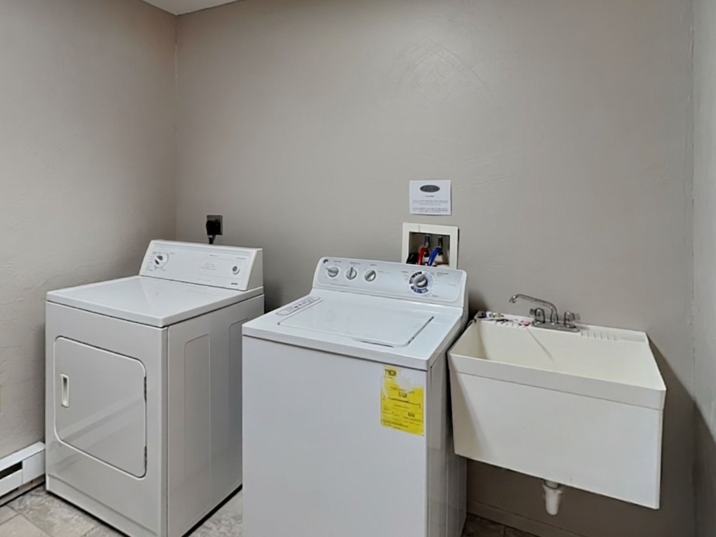 A laundry area with two washing machines and a sink.