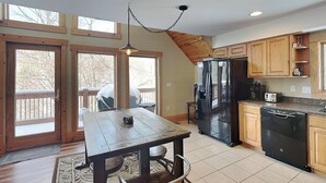 Une cuisine avec des meubles de rangement en bois, un réfrigérateur, un lave-vaisselle et une table à manger avec des chaises.