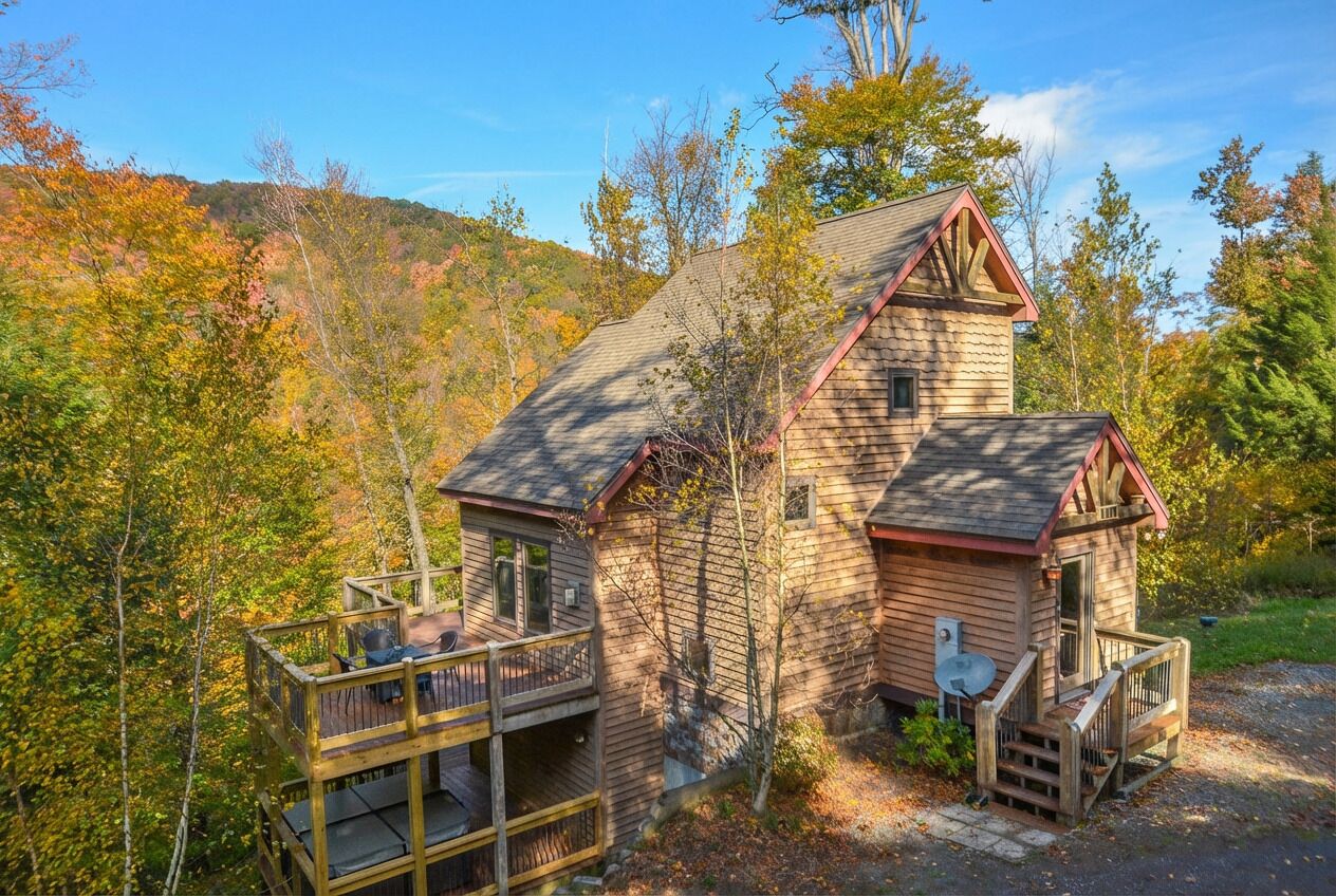 A cabin with a deck, a chimney, and a satellite dish.