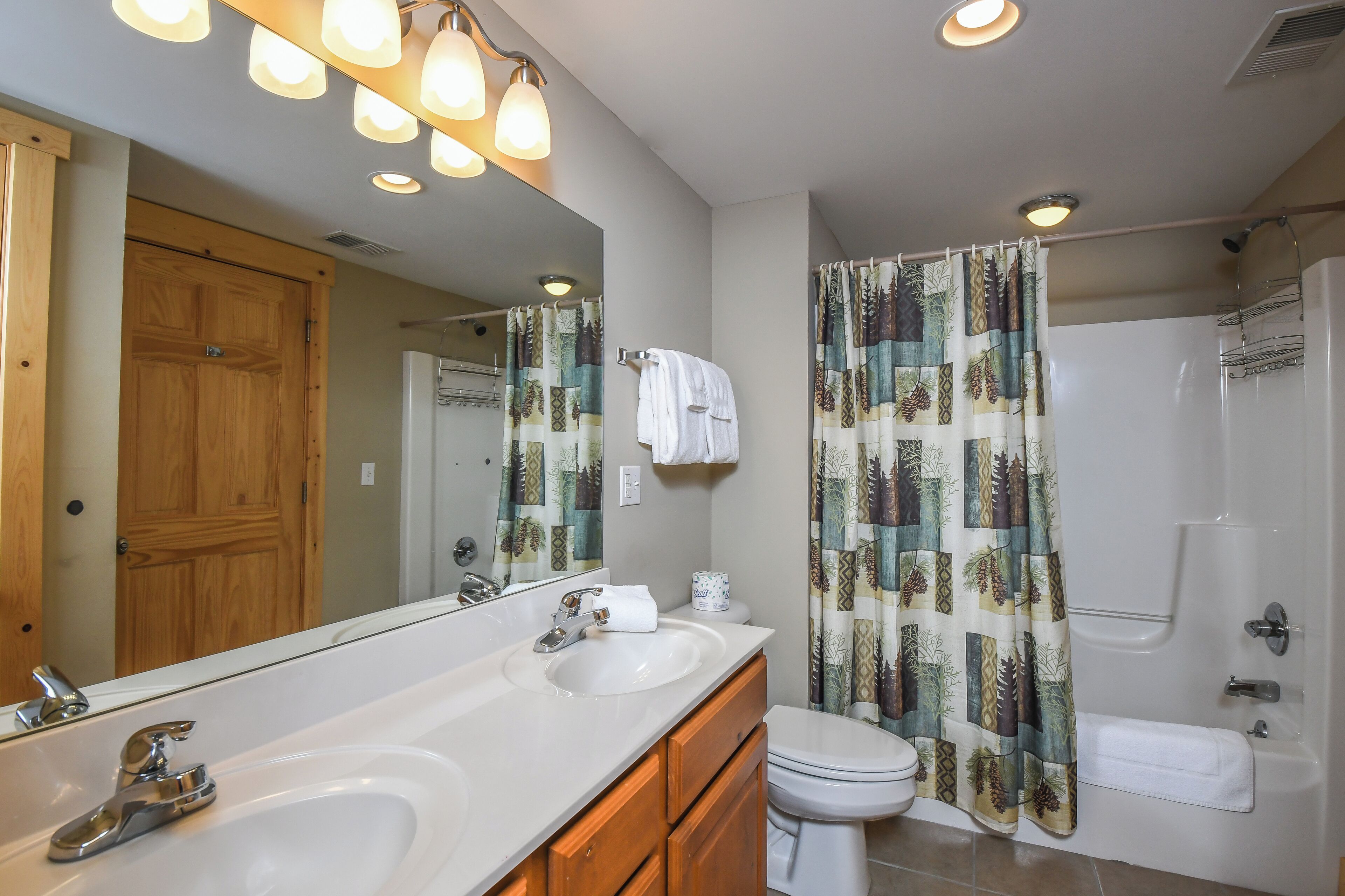 A bathroom with two sinks, a toilet, a shower, and a large mirror.