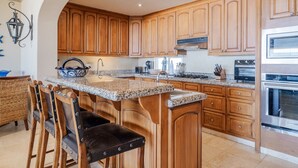 Eine Küche mit Holzschränken, Granit-Arbeitsplatten, einem eingebauten Herd und einem Essbereich mit Stühlen.