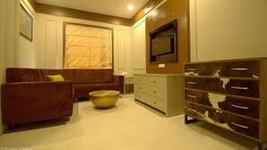 A living room with a sofa, a coffee table, a television, and a cabinet. - Amritam Palace (Jodhpur)