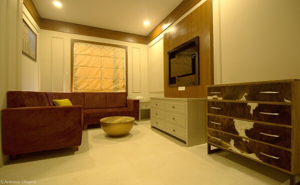A living room with a sofa, a coffee table, a television, and a cabinet. - Amritam Palace (Jodhpur)
