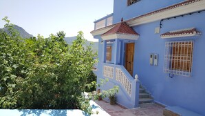 A blue building with a wooden door, a staircase, and a balcony with white balustrades. - Gite Talassemtane, a cosy guesthouse in the middle of nature in Chefchaouen area (Chefchaouen)