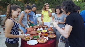 A group of people around a table with various dishes and utensils, indicating a communal meal setting. - Gite Talassemtane, a cosy guesthouse in the middle of nature in Chefchaouen area (Chefchaouen)