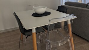 Ruokailutila, jossa on valkoinen pöytä, mustat tuolit ja valkoinen kulho mustan alustan päällä.