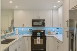 Enjoy cooking in this well-equipped kitchen with a stainless steel refrigerator, black stove, and microwave.